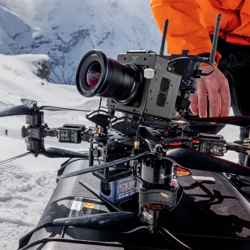 Pilot preparing a cinema FPV drone on a snowy mountain