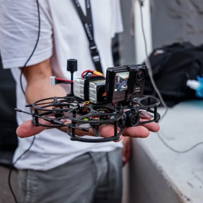Compact ducted FPV cinewhoop drone with an action camera, held in a pilot's hand