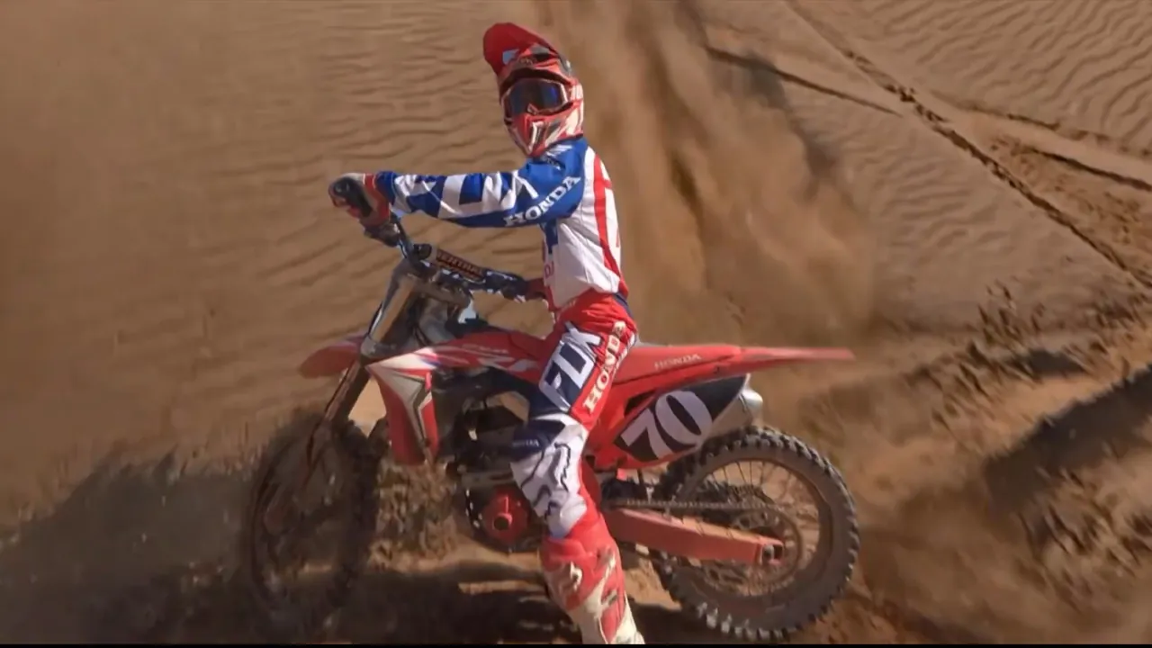 FPV drone shot of a motocross rider spraying sand in the desert