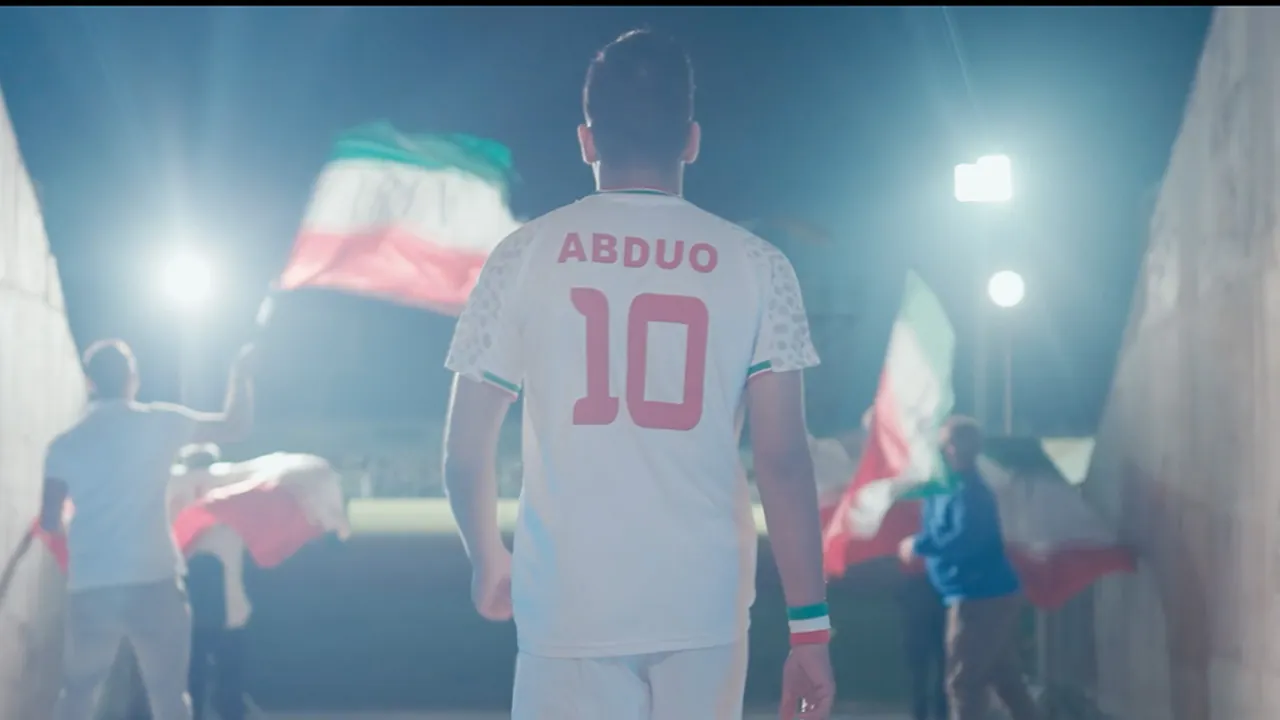 Iran national team player walking through a stadium tunnel with flags waving